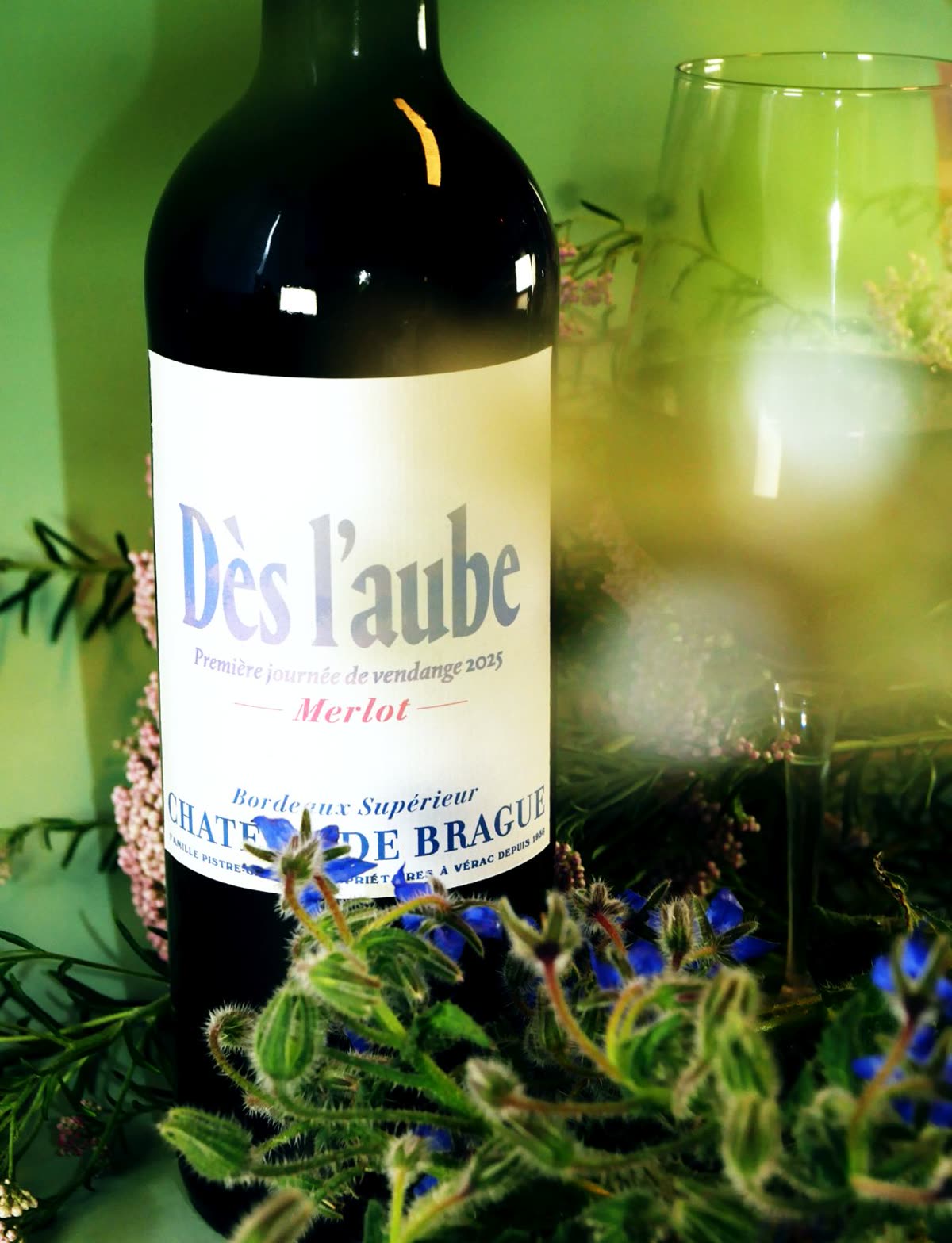 Bouteille Dès l'aube et verre parmi les fleurs